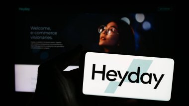 Stuttgart, Almanya - 05-14-2024: ABD e-ticaret inkübatör platformu şirketi Heyday 'in logosuna sahip akıllı telefon sahibi kişi web sitesinin önünde. Telefon ekranına odaklan.