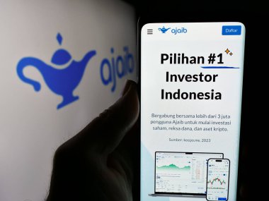 Stuttgart, Almanya - 05-16-2024: İnternet aracılığı şirketi PT Ajaib Teknologi Endonezya 'nın internet sayfası ile logo önünde cep telefonu tutan kişi. Telefon ekranının merkezine odaklan.