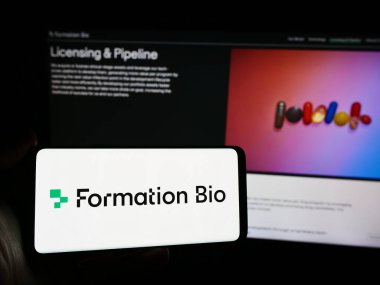 Stuttgart, Almanya - 05-16-2024: Amerikan biyoteknoloji şirketi Formation Bio Inc. 'in logosunun bulunduğu cep telefonu sahibi kişi iş sayfasının önünde. Telefon ekranına odaklan.