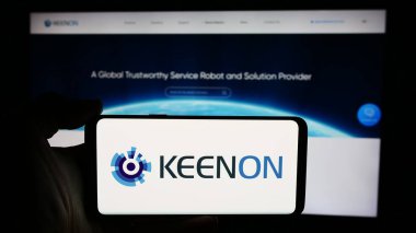Stuttgart, Almanya - 05-16-2024: Çinli hizmet robotu şirketi Keenon Robotics Co. Ltd. 'nin logosuyla cep telefonu tutan kişi web sayfasının önünde. Telefon ekranına odaklan.