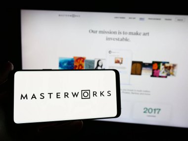 Stuttgart, Almanya - 05-16-2024: ABD 'li sanat yatırım şirketi Masterworks LLC' nin logosuna sahip akıllı telefon sahibi kişi web sitesi önünde. Telefon ekranına odaklan.