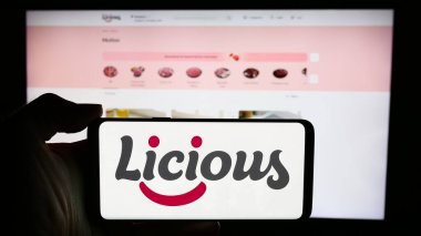 Stuttgart, Almanya - 05-16-2024: Üzerinde Hint gıda dağıtım şirketi Licious 'un logosu bulunan cep telefonu sahibi kişi iş sayfasının önünde. Telefon ekranına odaklan.