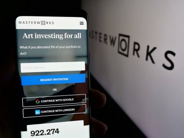 Stuttgart, Almanya - 05-16-2024: ABD 'li sanat yatırım şirketi Masterworks LLC' nin web sayfası ile logo önünde cep telefonu tutan kişi. Telefon ekranının merkezine odaklan.