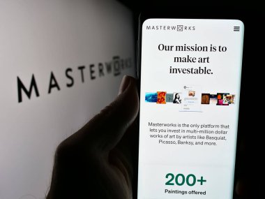 Stuttgart, Almanya - 05-16-2024: ABD 'li sanat yatırım şirketi Masterworks LLC' nin web sayfası ile logo önünde cep telefonu tutan kişi. Telefon ekranının merkezine odaklan.