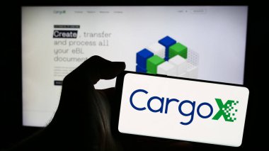 Stuttgart, Almanya - 05-15-2024: Sloven engelleme teknolojisi şirketi CargoX Ltd. 'nin logosuna sahip cep telefonu sahibi kişi web sayfasının önünde. Telefon ekranına odaklan.