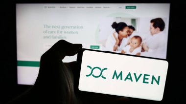 Stuttgart, Almanya - 05-16-2024: Amerikan sanal sağlık şirketi Maven Clinic Co. 'nun logosunu taşıyan cep telefonu sahibi kişi iş sayfasının önünde. Telefon ekranına odaklan.