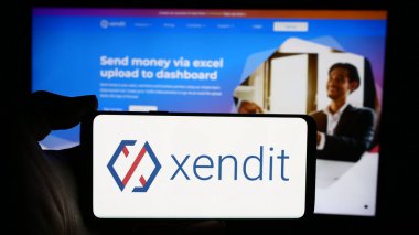 Stuttgart, Almanya - 05-16-2024: Endonezyalı PT Sinar Dijital Terdepan (Xendit) şirketinin logosunun bulunduğu cep telefonu sahibi kişi iş sayfası önünde. Telefon ekranına odaklan.