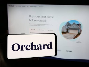 Stuttgart, Almanya - 05-16-2024: İnternet sitesi önünde üzerinde ABD 'li emlak platformu şirketi Orchard Technologies Inc.' in logosu olan akıllı telefon sahibi kişi. Telefon ekranına odaklan.