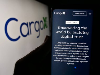Stuttgart, Almanya - 05-15-2024: Sloven engelleme teknolojisi şirketi CargoX Ltd. 'nin web sayfası ile logo önünde cep telefonu tutan kişi. Telefon ekranının merkezine odaklan.