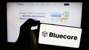 Stuttgart, Almanya - 05-17-2024: İnternet sayfası önünde üzerinde Amerikan pazarlama teknolojisi şirketi Bluecore Inc. 'in logosu bulunan cep telefonu sahibi kişi. Telefon ekranına odaklan.