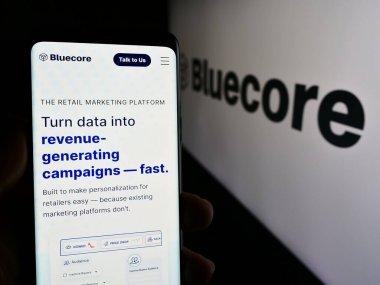Stuttgart, Almanya - 05-17-2024: ABD 'li pazarlama teknoloji şirketi Bluecore Inc.' in web sayfası ile logo önünde cep telefonu tutan kişi. Telefon ekranının merkezine odaklan.
