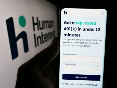 Stuttgart, Almanya - 05-17-2024: ABD 'li finans şirketi Human Interest Inc.' in web sayfası ile logo önünde akıllı telefon tutan kişi. Telefon ekranının merkezine odaklan.