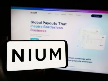 Stuttgart, Almanya - 05-17-2024: Singapur ödeme şirketi Nium Pte 'nin logosuna sahip kişi. Ltd. Web sitesinin önünde. Telefon ekranına odaklan.