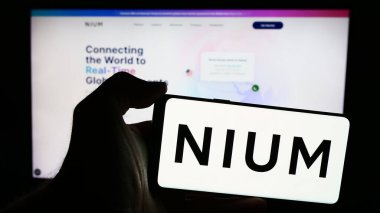 Stuttgart, Almanya - 05-17-2024: Singapur ödeme şirketi Nium Pte 'nin logosuna sahip cep telefonu sahibi kişi. Ltd. İş sayfasının önünde. Telefon ekranına odaklan.