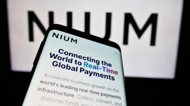 Stuttgart, Germany - 05-17-2024: Mobile phone with website of Singaporean payments company Nium Pte. Ltd. in front of business logo. Focus on top-left of phone display. clipart