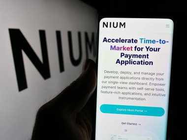 Stuttgart, Almanya - 05-17-2024: Singapur ödeme şirketi Nium Pte 'nin internet sayfası ile akıllı telefon sahibi kişi. Ltd. Logonun önünde. Telefon ekranının merkezine odaklan.