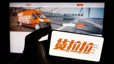 Stuttgart, Almanya - 05-17-2024: Çinli lojistik platformu şirketi Huolala 'nın logosuna sahip akıllı telefon sahibi kişi web sitesinin önünde. Telefon ekranına odaklan.