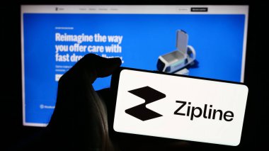 Stuttgart, Almanya - 05-21-2024: İnternet sayfasının önünde Amerikan insansız hava aracı dağıtım şirketi Zipline International Inc. 'in logosuna sahip cep telefonu sahibi kişi. Telefon ekranına odaklan.