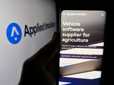 Stuttgart, Almanya - 05-21-2024: ABD 'li araç yazılım şirketi Applied Intuition Inc.' in web sayfası ile logo önünde cep telefonu tutan kişi. Telefon ekranının merkezine odaklan.