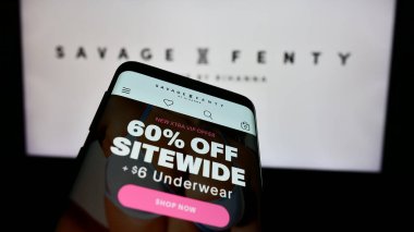Stuttgart, Almanya - 05-15-2024: ABD 'li moda şirketi Savage X Fenty' nin web sitesiyle birlikte iş logosu önünde cep telefonu. Telefon ekranının sol üst kısmına odaklan.