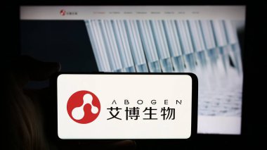 Stuttgart, Germany - 05-21-2024: Person holding cellphone with logo of Chinese company Suzhou Abogen Biosciences Co. Ltd. in front of business webpage. Focus on phone display. clipart