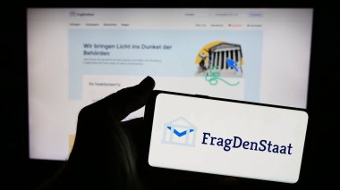 Stuttgart, Almanya - 05-21-2024: İnternet sitesi önünde Alman sivil toplum örgütü FragDenStaat 'ın logosuna sahip kişi. Telefon ekranına odaklan.