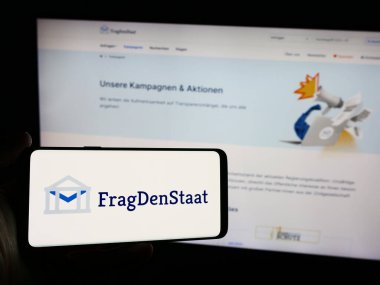 Stuttgart, Almanya - 05-21-2024: Alman sivil toplum örgütü FragDenStaat 'ın logosunun bulunduğu cep telefonu web sayfası önünde duruyor. Telefon ekranına odaklan.