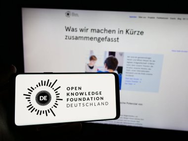 Stuttgart, Almanya - 05-21-2024: Açık Bilgi Vakfı Deutschland E.V. logosu olan cep telefonu sahibi kişi (OKFDE) Web sayfasının önünde. Telefon ekranına odaklan.