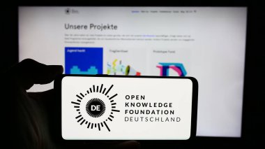 Stuttgart, Almanya - 05-21-2024: Açık Bilgi Vakfı Deutschland E.V. logosuna sahip akıllı telefon sahibi kişi (OKFDE) web sitesinin önünde. Telefon ekranına odaklan.