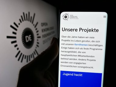Stuttgart, Almanya - 05-21-2024: Cep telefonunda Deutschland E.V. Açık Bilgi Vakfı web sayfası bulunan kişi (OKFDE) Logonun önünde. Telefon ekranının merkezine odaklan.