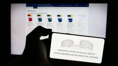 Stuttgart, Almanya - 05-21-2024: İnternet sayfası önünde uluslararası mahkeme Avrupa İnsan Hakları Mahkemesi (AİHM) logosu bulunan cep telefonu sahibi kişi. Telefon ekranına odaklan.