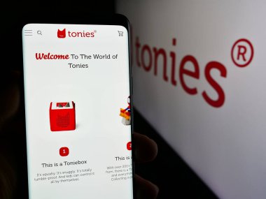 Stuttgart, Almanya - 05-22-2024: Alman oyuncak perakende şirketi Tonies SE 'nin (Toniebox) web sayfası ile logo önünde cep telefonu tutan kişi. Telefon ekranının merkezine odaklan.