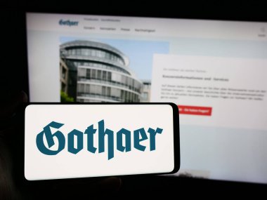 Stuttgart, Almanya - 05-22-2024: Alman sigorta şirketi Gothaer Versicherungsbank VVaG 'ın logosuna sahip akıllı telefon sahibi kişi web sitesi önünde. Telefon ekranına odaklan.