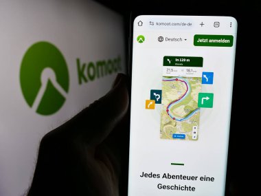 Stuttgart, Almanya - 05-23-2024: Logonun önünde Alman rota planlama uygulaması komoot GmbH web sayfası bulunan cep telefonu sahibi kişi. Telefon ekranının merkezine odaklan.