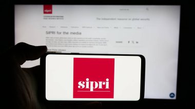 Stuttgart, Almanya - 05-23-2024: Stockholm Uluslararası Barış Araştırma Enstitüsü 'nün (SIPRI) logosuna sahip cep telefonu sahibi kişi web sayfası önünde. Telefon ekranına odaklan.