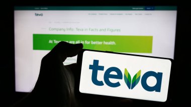 Stuttgart, Almanya - 05-23-2024: İsrailli Teva Pharmaceutical Industries Ltd. 'nin logosunun bulunduğu cep telefonu sahibi kişi web sayfasının önünde. Telefon ekranına odaklan.