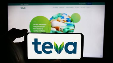 Stuttgart, Almanya - 05-23-2024: İsrailli Teva Pharmaceutical Industries Ltd. şirketinin logosunun bulunduğu cep telefonu sahibi kişi iş sayfası önünde. Telefon ekranına odaklan.
