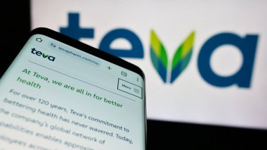 Stuttgart, Germany - 05-23-2024: Smartphone with webpage of Israeli company Teva Pharmaceutical Industries Ltd. in front of business logo. Focus on top-left of phone display. clipart