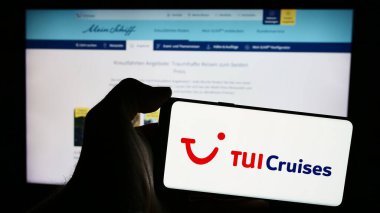 Stuttgart, Almanya - 05-23-2024: İnternet sayfası önünde Alman seyir hattı şirketi TUI Cruises GmbH 'un (Mein Schiff) logosuna sahip cep telefonu sahibi kişi. Telefon ekranına odaklan.