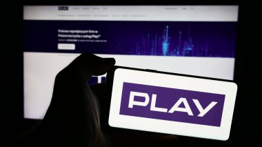 Stuttgart, Almanya - 05-23-2024: Polonya telekomünikasyon şirketi P4 sp 'nin logosuna sahip cep telefonu sahibi kişi. - Hoşça kal. (Play) Web sayfasının önünde. Telefon ekranına odaklan.