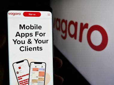 Stuttgart, Almanya - 05-15-2024: ABD 'nin sağlıklı pazar yeri şirketi Vagaro Inc.' in logolu web sayfası ile cep telefonu tutan kişi. Telefon ekranının merkezine odaklan.
