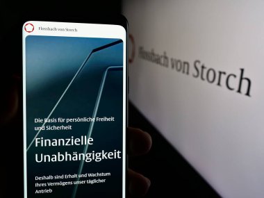 Stuttgart, Almanya - 05-24-2024: Alman servet yönetimi şirketi Flossbach von Storch AG 'nin logolu web sayfası ile cep telefonu tutan kişi. Telefon ekranının merkezine odaklan.