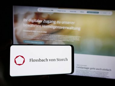 Stuttgart, Almanya - 05-24-2024: Alman servet yönetimi şirketi Flossbach von Storch AG 'nin logosunun bulunduğu akıllı telefon sahibi kişi web sitesi önünde. Telefon ekranına odaklan.
