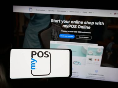Stuttgart, Almanya - 05-27-2024: İngiliz ödeme teknolojisi şirketi myPOS World Ltd. nin logosuna sahip akıllı telefon sahibi kişi web sitesinin önünde. Telefon ekranına odaklan.