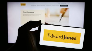 Stuttgart, Almanya - 05-27-2024: ABD 'li finans hizmetleri şirketi Edward Jones Investments' ın logosuyla cep telefonu sahibi kişi web sayfası önünde. Telefon ekranına odaklan.