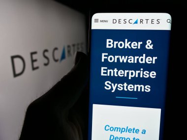 Stuttgart, Almanya - 05-27-2024: Kanadalı şirket The Descartes Systems Group Inc. 'in web sayfası ile logo önünde akıllı telefon tutan kişi. Telefon ekranının merkezine odaklan.