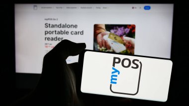 Stuttgart, Almanya - 05-27-2024: İngiliz ödeme teknolojisi şirketi myPOS World Ltd. 'nin logosuna sahip cep telefonu sahibi kişi web sayfasının önünde. Telefon ekranına odaklan.