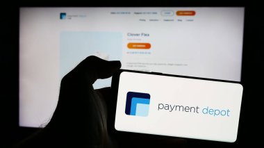 Stuttgart, Almanya - 05-27-2024: İnternet sayfası önünde üzerinde ABD kart işleme şirketi Payment Depot 'un (Stax Payments) logosu bulunan cep telefonu sahibi kişi. Telefon ekranına odaklan.