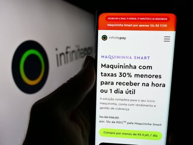 Stuttgart, Almanya - 05-27-2024: Brezilyalı finans platformu şirketi InfinitePay 'in logo önündeki web sitesi ile akıllı telefon sahibi kişi. Telefon ekranının merkezine odaklan.