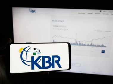 Stuttgart, Almanya - 05-27-2024: İnternet sayfası önünde üzerinde Amerikan mühendislik ve inşaat şirketi KBR Inc. 'in logosu bulunan cep telefonu sahibi kişi. Telefon ekranına odaklan.